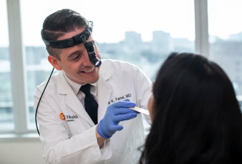 Dr. Ferrell examines a patient's mouth using a tongue depressor.
